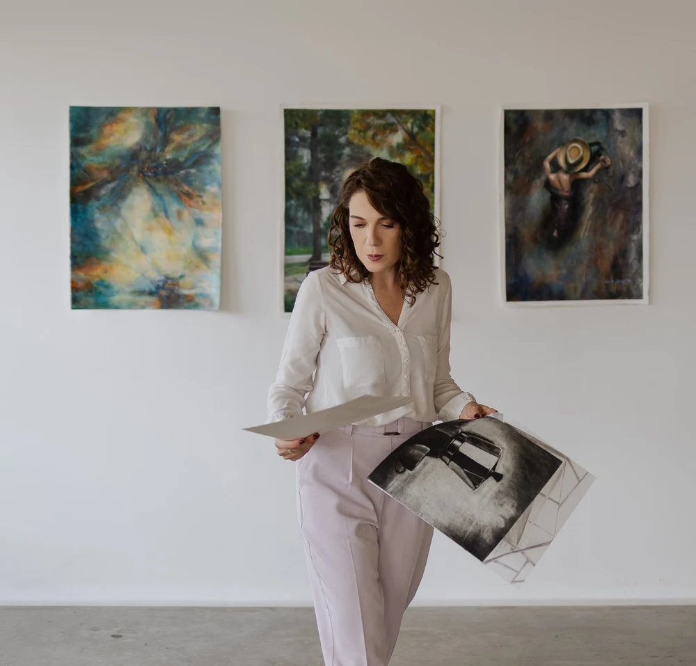 Ana Steffler no ateliê com obras ao fundo