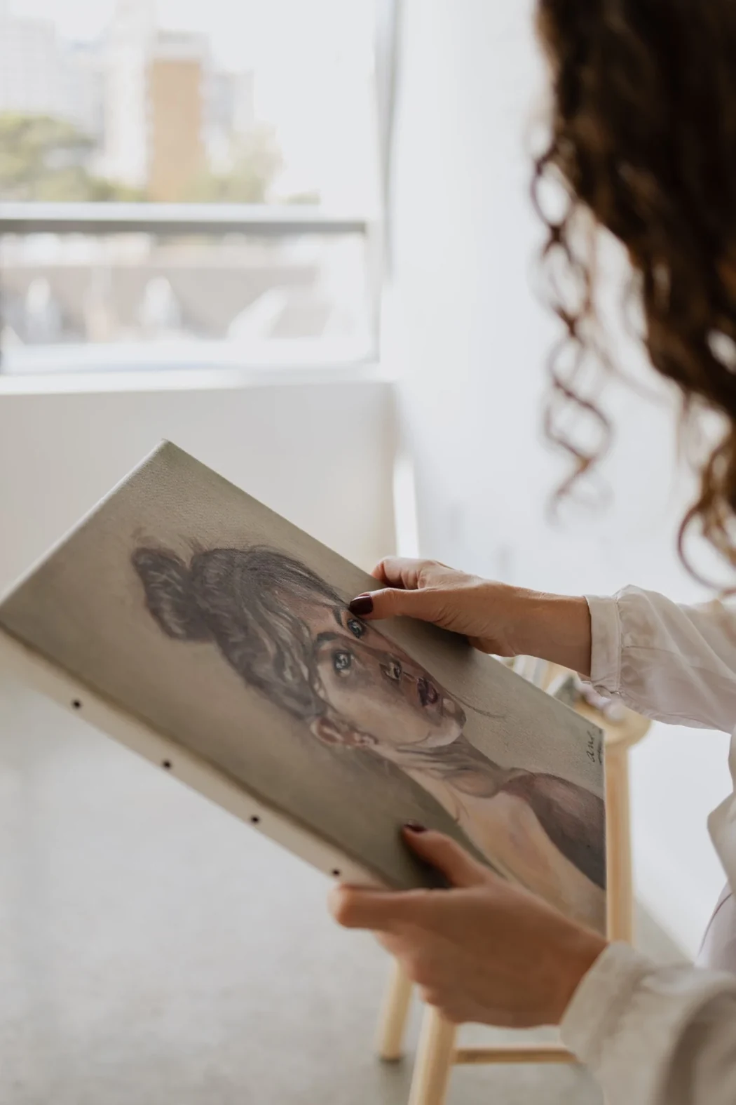 Ana Steffler holding a portrait painting in the studio